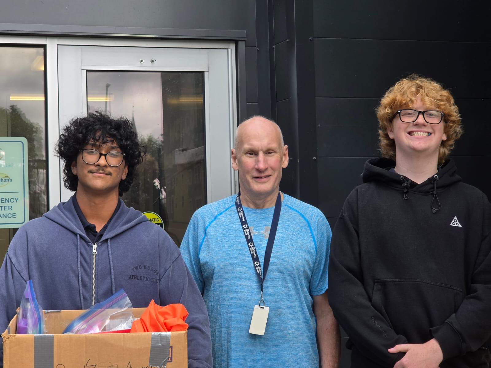 Two young volunteers with a community partner after a donation activity
